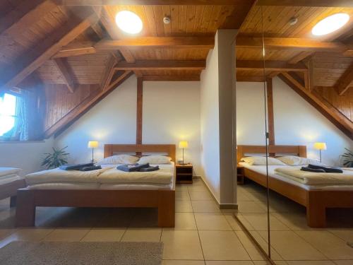 two beds in a room with wooden ceilings at Centrum Slezská Harta in Razová