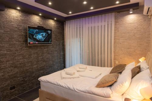 a bedroom with a bed with a tv on a brick wall at Art Lux apartman in Kruševac