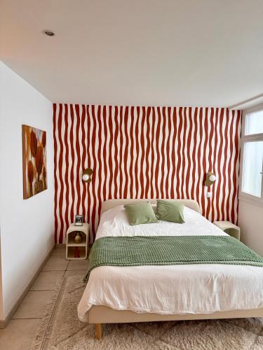 a bedroom with a bed with a red and white striped wall at Duplex Trespoey - SPA - Place de parking in Pau