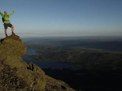 a man standing on the top of a mountain at Modern cabin, great view, sunny, 2BA, 4BR in Hemsedal