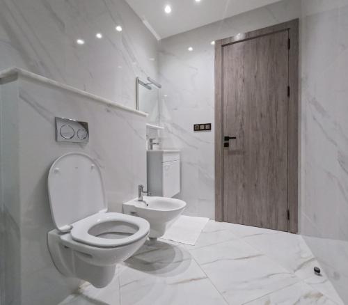 a white bathroom with a toilet and a wooden door at Living Appart-Hotel in Tangier