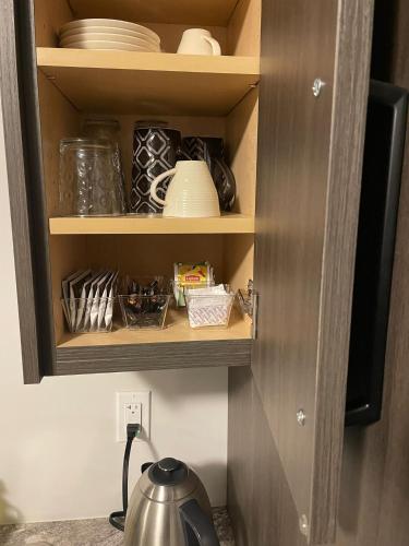 a cupboard with dishes and plates and a tea kettle at Modern, well-equipped, and centrally located in Fonthill