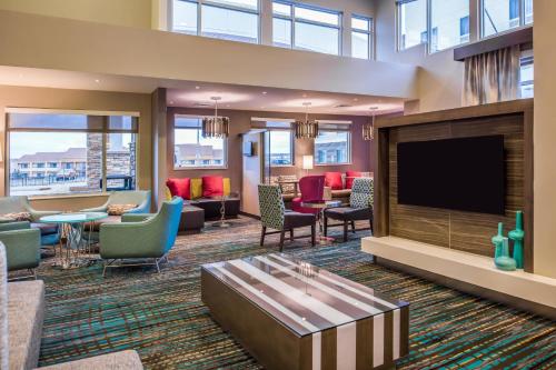 a hotel lobby with a tv and chairs and tables at Residence Inn by Marriott St. Louis Westport in Maryland Heights