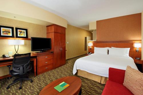 a hotel room with a bed and a desk and a tv at Courtyard by Marriott St. George in St. George