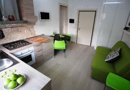 a kitchen with green chairs and a table with a sink at La Finestra Su Roma in Frascati