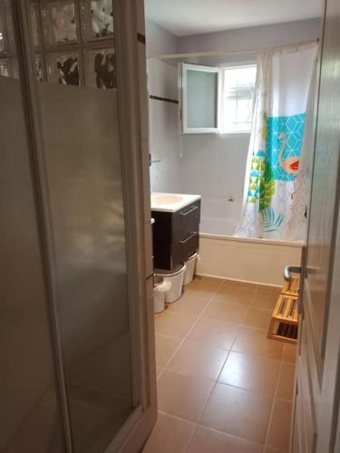 La salle de bains est pourvue d'un lavabo et d'une porte de douche en verre. dans l'établissement Maison de campagne avec piscine proche Carcassonne, à Raissac-sur-Lampy