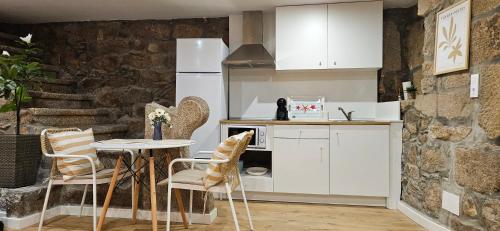 a kitchen with white cabinets and a table and chairs at Apartamentos Mirador de San Telmo in Tui
