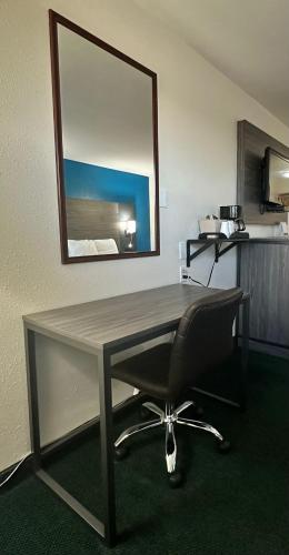 a desk with a chair in a room with a mirror at Super 7 Inn Tecumseh in Tecumseh