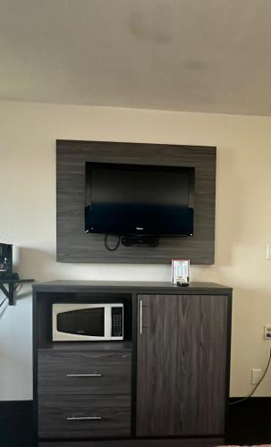 a room with a microwave and a television on a wall at Super 7 Inn Tecumseh in Tecumseh