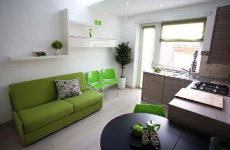 a living room with a green couch and a kitchen at La Finestra Su Roma in Frascati