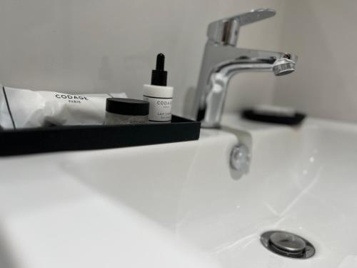 - un lavabo avec une bouteille de rouge à lèvres et un robinet dans l'établissement Oberkampf by Melvane 21, à Paris