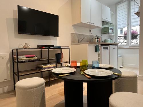 - un salon avec une table, des chaises et une télévision dans l'établissement Oberkampf by Melvane 21, à Paris