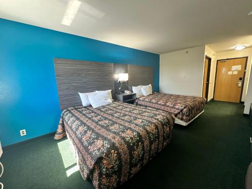 a hotel room with two beds and a blue wall at Super 7 Inn Tecumseh in Tecumseh