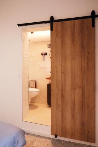 Une porte coulissante mène à une salle de bains avec toilettes. dans l'établissement Séjour Chic et Cosy au Cœur de Versailles, à Versailles