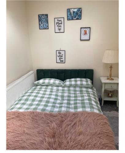 a green and white bed with four pictures on the wall at Studio with private shower and toilet in Hadleigh