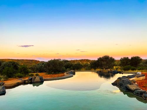 a pool of water with a sunset in the background at Ooraminna Homestead in Alice Springs