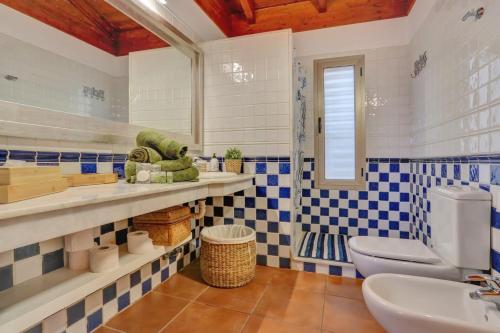 un bagno con piastrelle blu e bianche e un water di Villa Charly a Puerto de la Madera