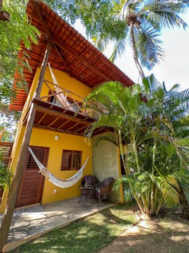 a yellow house with a hammock in front of it at Aldeia Maracajaú - Camping & Chalés in Maracajaú
