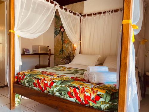 a bedroom with a canopy bed with towels on it at Villa Baobá Pousada & Spa in Búzios