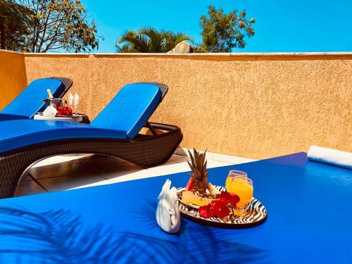 a blue table with a plate of fruit and a glass of orange juice at Villa Baobá Pousada & Spa in Búzios