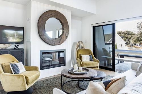 a living room with a couch and chairs and a fireplace at Wainui Townhouses in Raglan