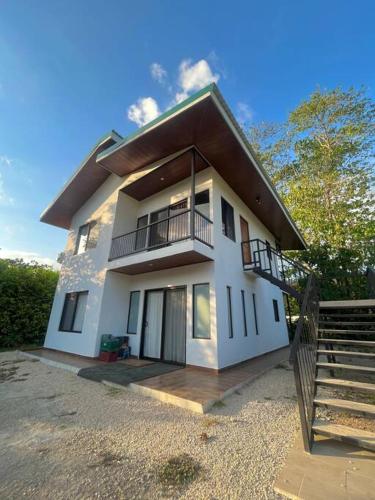 a large white house with a balcony and stairs at Villa Marina, Nosara in Nosara