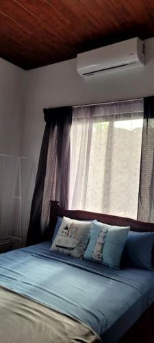 a bedroom with a bed with a window and pillows at Villa Marina, Nosara in Nosara