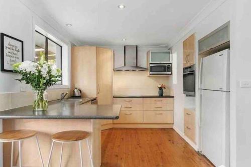 een keuken met een aanrecht met krukken en een koelkast bij DOCK 08 Riverside Entertainer Pets Welcome in Chittaway Point
