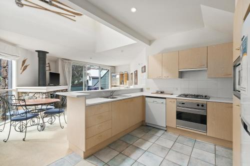 a kitchen with white appliances and a table and chairs at Wintergreen 11 in Thredbo