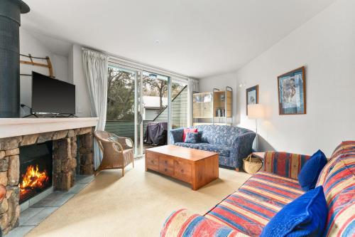 a living room with a couch and a fireplace at Wintergreen 11 in Thredbo