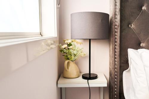 a lamp on a side table with a vase of flowers at Bright Modern Holiday Home 7 Beds at Doncaster in Doncaster