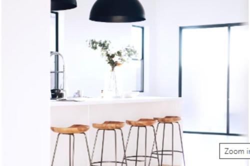 a kitchen with three bar stools under a black lamp at Letty's Happy Place in Midsayap
