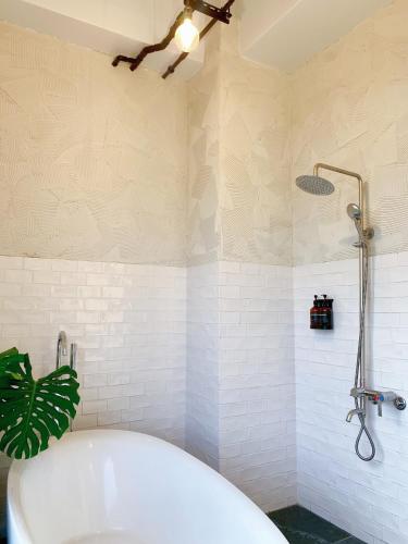 a bathroom with a white tub and a shower at Still Hills Inn in Hengchun