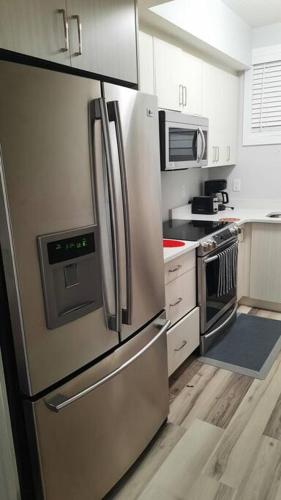 a kitchen with a stainless steel refrigerator and a microwave at Carsonway Basement Suite in Edmonton