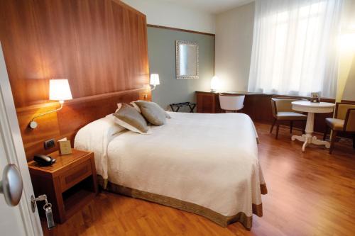 a hotel room with a large bed and a table at Albergo Celide in Lucca
