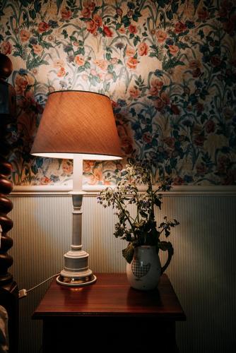 a lamp and a vase on a table with flowers at The Rabbiter's Cottage in Kahuranaki