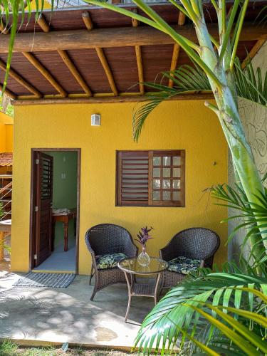 a patio with wicker chairs and a table in front of a house at Aldeia Maracajaú - Camping & Chalés in Maracajaú