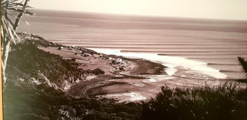 a group of people on a beach near the ocean at Whale Bay's Surf Meca holiday accommodation in Raglan