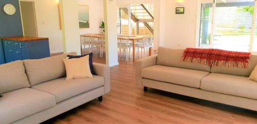 a living room with two couches and a table at Whale Bay's Surf Meca holiday accommodation in Raglan