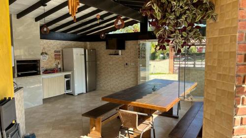 una cucina con un tavolo di legno e una sala da pranzo di Linda casa Morada da Praia com piscina privativa e muito espaço pra você e seu pet a Bertioga