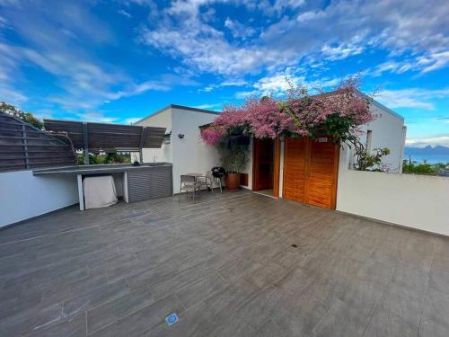 a white house with a wooden door and a patio at Fare Miri Ata Premium - 107m2 Panoramic view in Punaauia