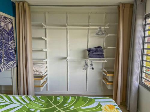 a bedroom with a closet with shelves and a bed at Fare Miri Ata Premium - 107m2 Panoramic view in Punaauia