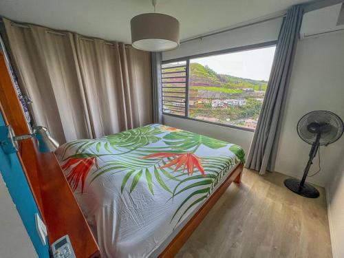a bedroom with a bed and a window with a fan at Fare Miri Ata Premium - 107m2 Panoramic view in Punaauia