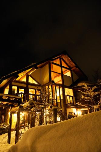 a large building with lights in the snow at night at Hakuba Pension & Log Hotel Meteor in Hakuba