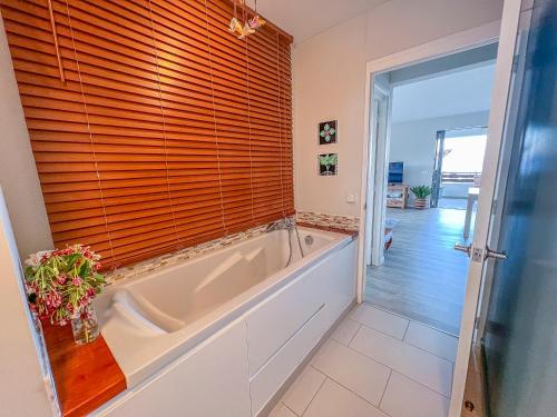 a bath tub in a bathroom with a window at Fare Miri Ata Premium - 107m2 Panoramic view in Punaauia