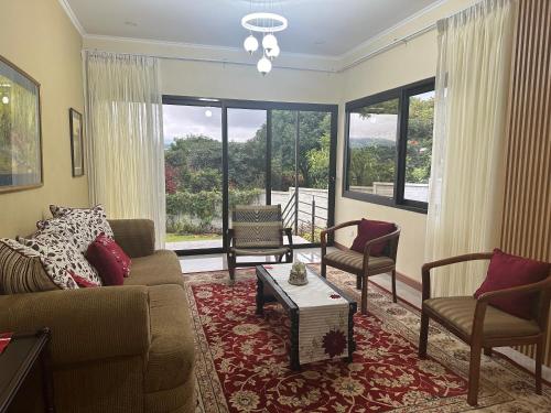 a living room with a couch and chairs and windows at Apartamento Gratitud in Alajuela City