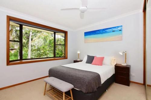Un dormitorio con una cama grande y una ventana. en All Decked Out at Hyams Beach by Experience Jervis, en Hyams Beach