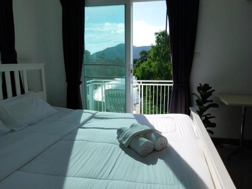 Un dormitorio con una cama blanca con una ventana grande. en Charlie's Angels Hotel Restaurant, en Rawai Beach