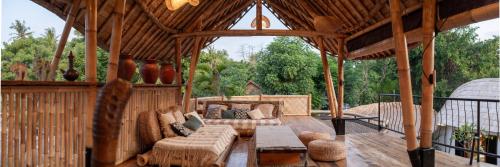 a large wooden porch with a couch and a table at Villa Samyama in Gili Air