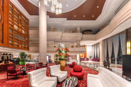 a hotel lobby with white couches and red chairs at Plaza Hotel Yuyao in Yuyao